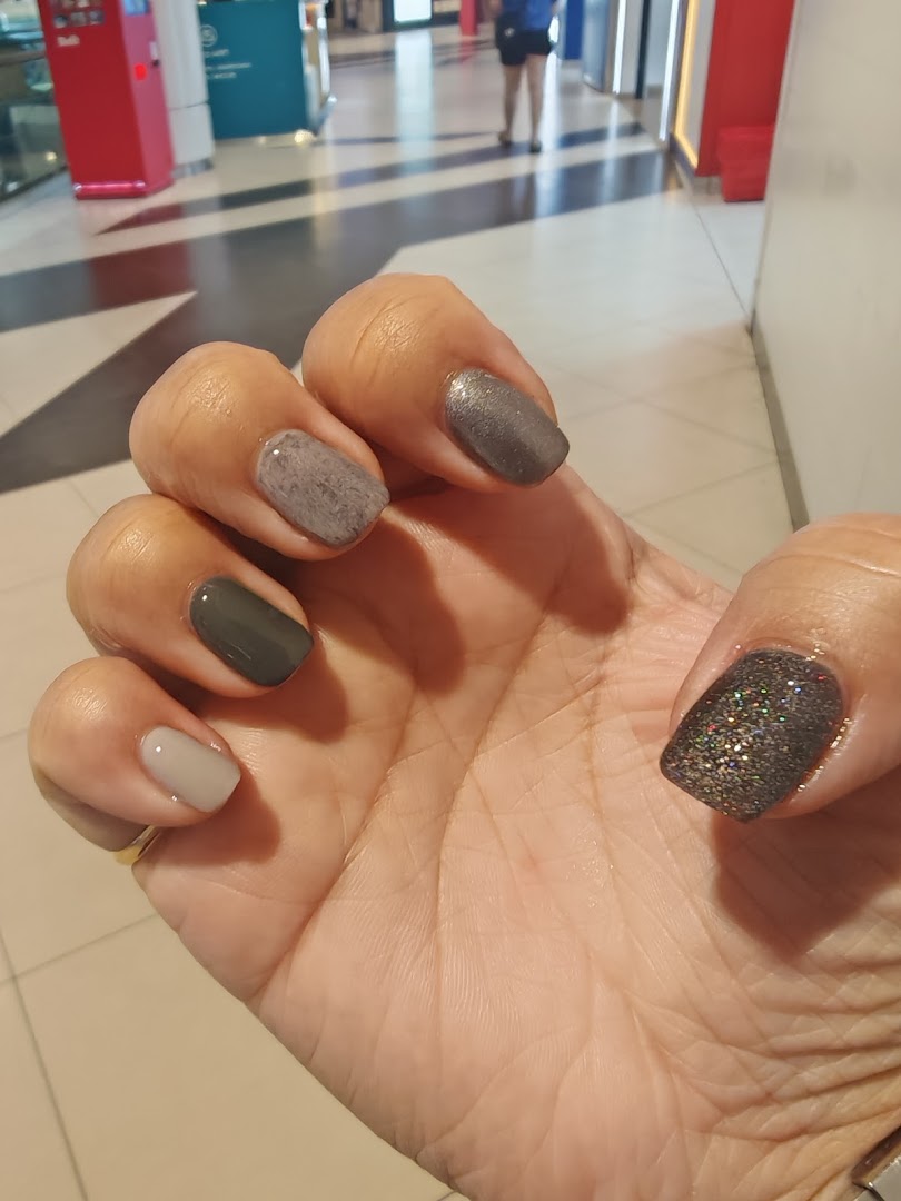 A hand showcasing freshly painted nails with various shades and textures.