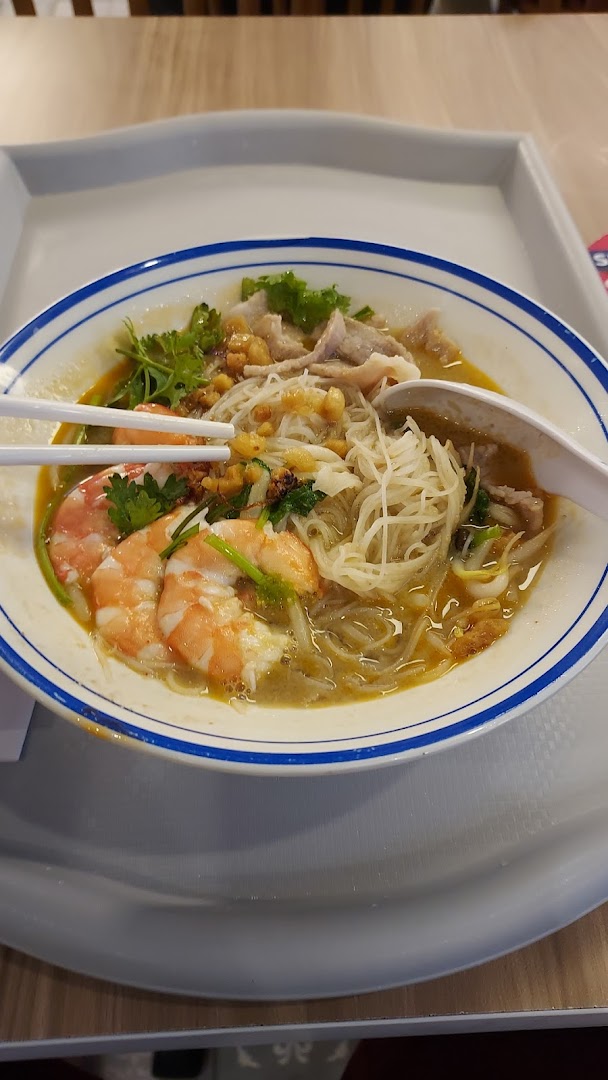 A close-up of a delicious bowl of prawn and pork noodle soup with chopsticks.