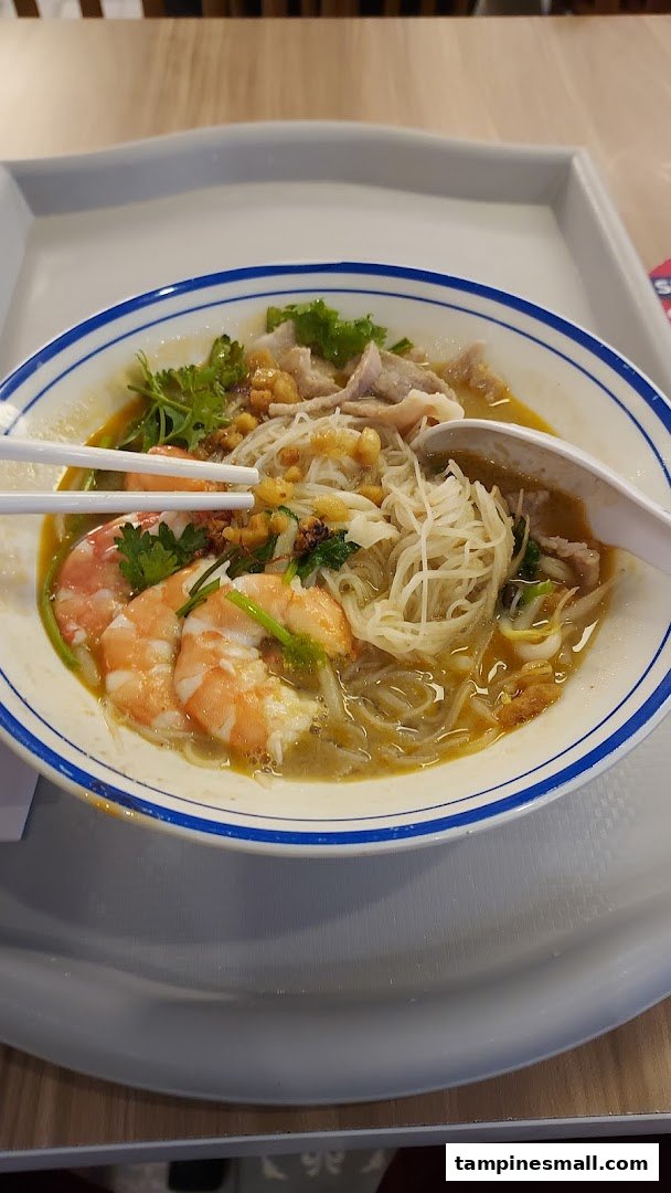 A close-up of a delicious bowl of prawn and pork noodle soup with chopsticks.