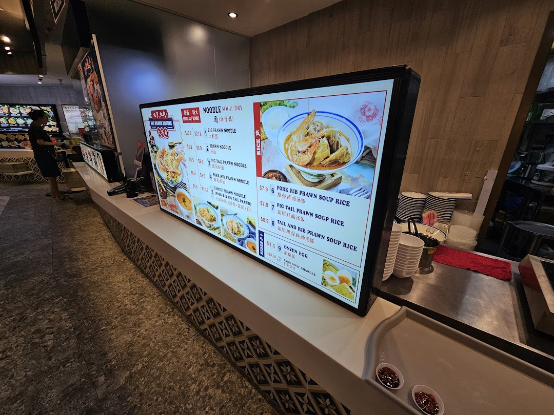 A digital menu board displaying various prawn noodle and rice dishes with prices at Jiaxins Prawn Noodle.