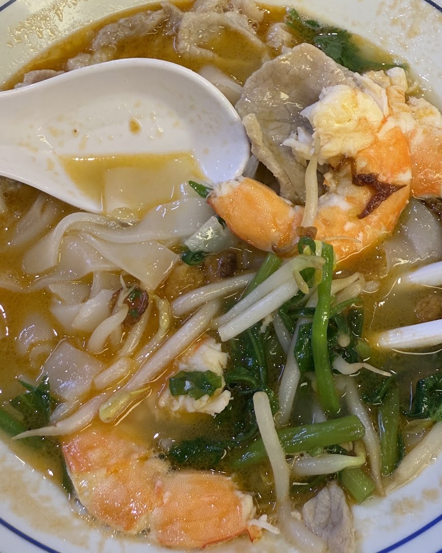 A close-up of a delicious bowl of prawn noodles with fresh ingredients.