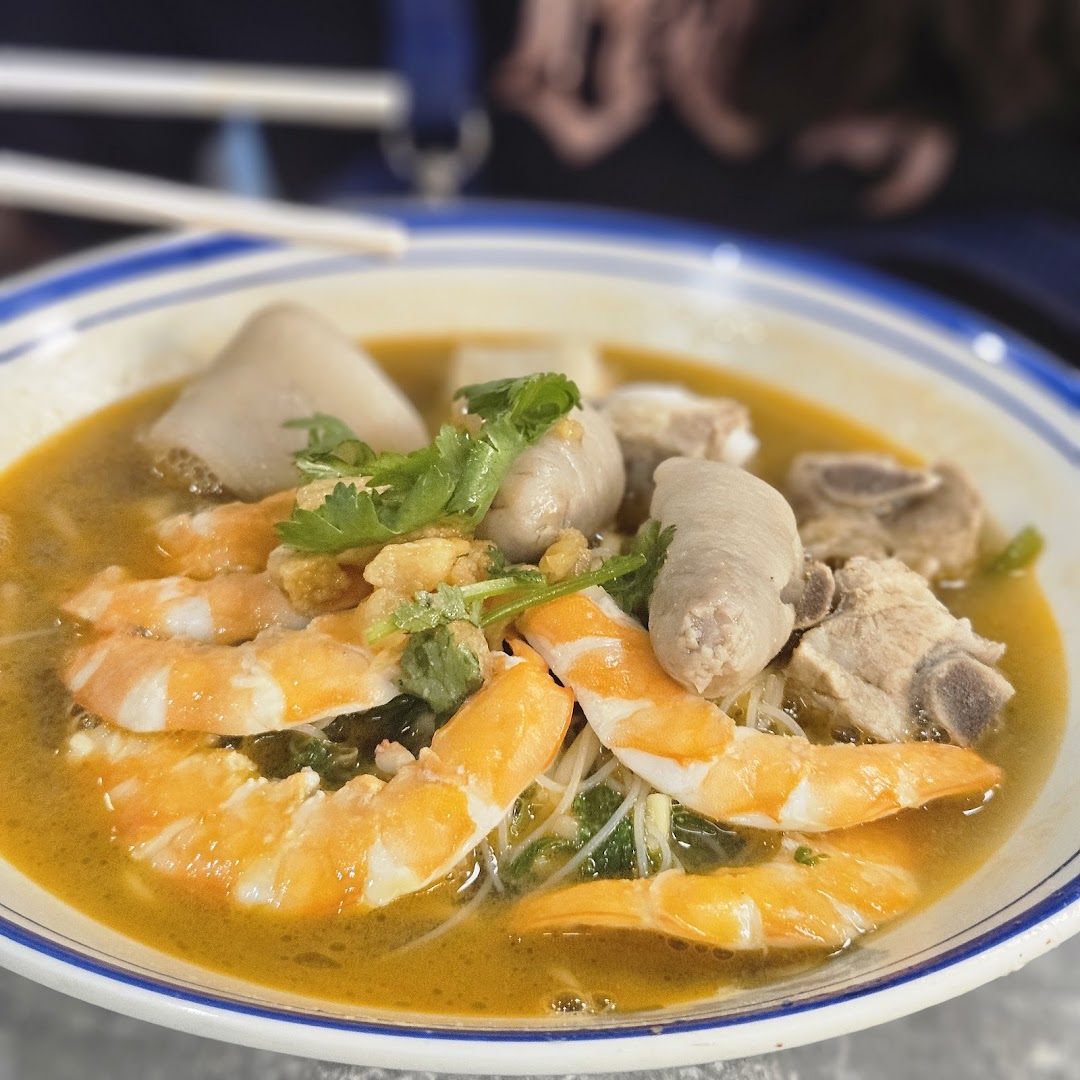A vibrant bowl of prawn noodles with shrimp, pork ribs, and other delicious ingredients.