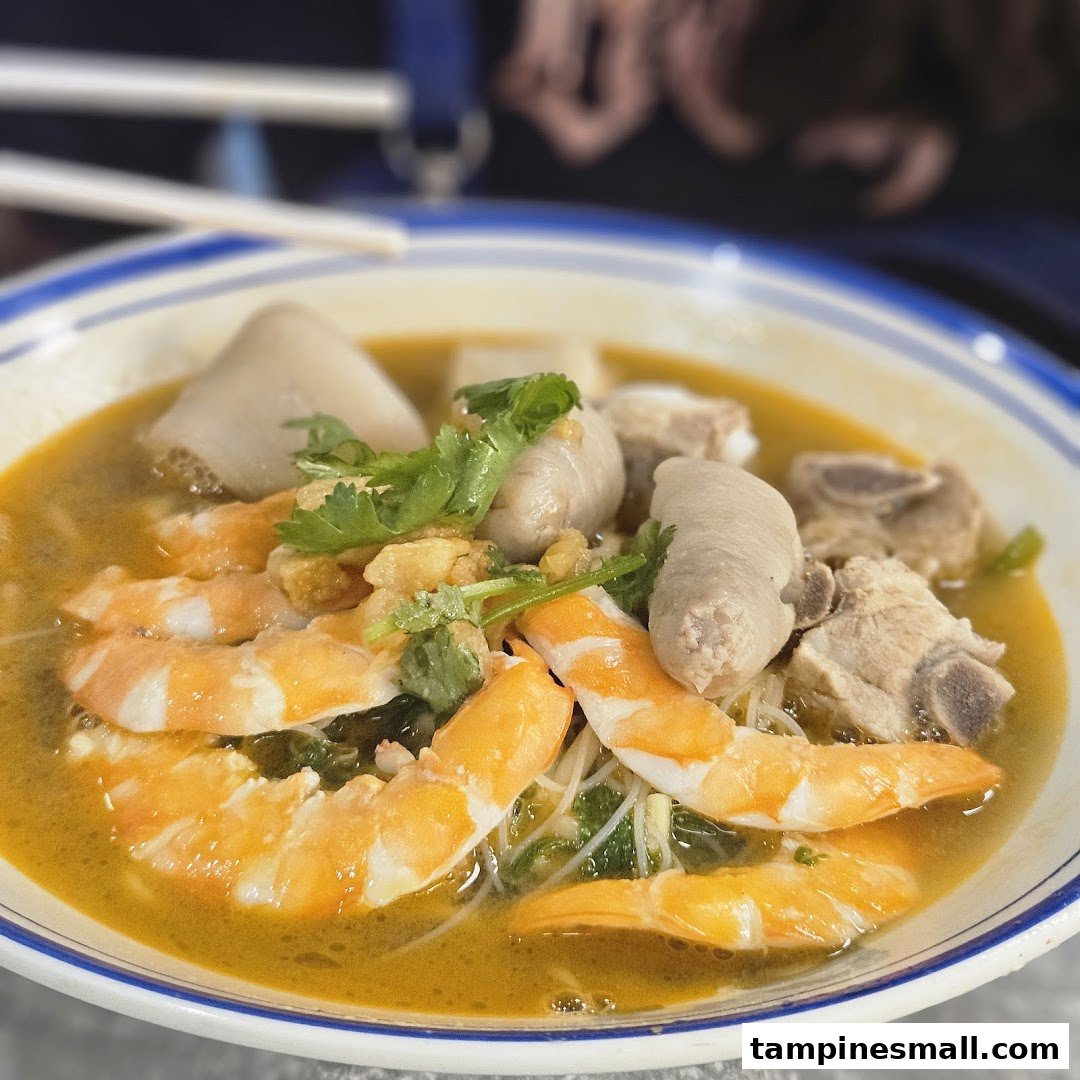 A vibrant bowl of prawn noodles with shrimp, pork ribs, and other delicious ingredients.