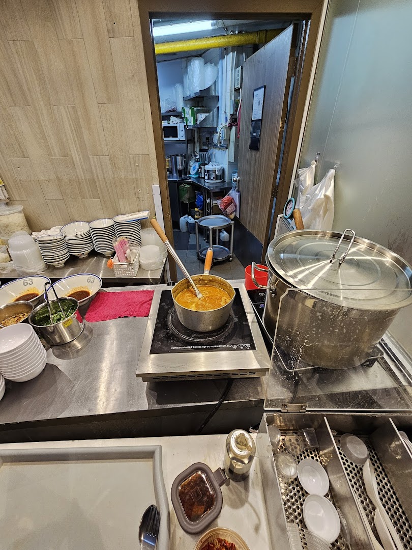 A bustling kitchen counter at Jiaxins Prawn Noodle, showcasing fresh ingredients and cooking in progress.