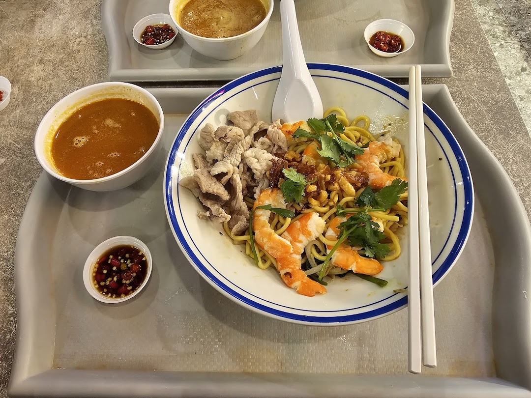 A delicious bowl of prawn noodles with soup, shrimp, and pork slices on a tray.