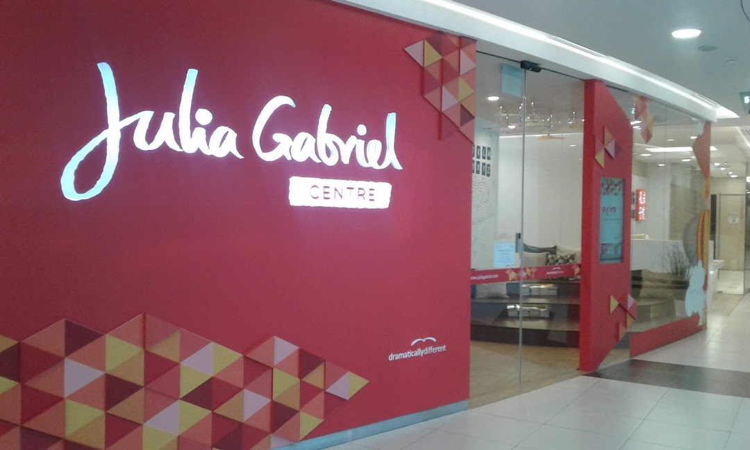 The bright red storefront of Julia Gabriel Centre with its illuminated logo and glass entrance.
