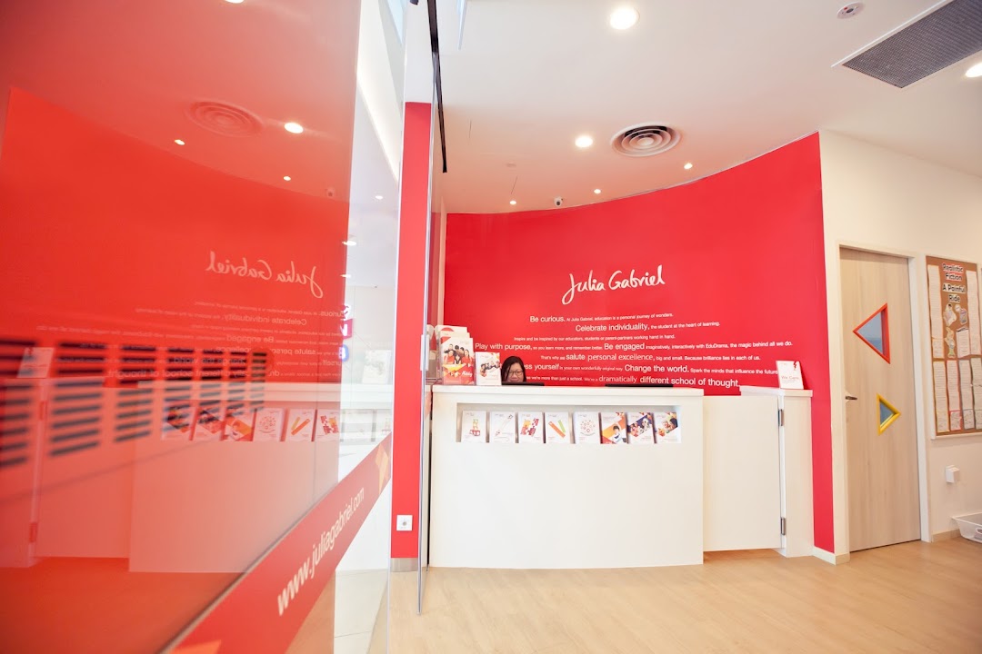 Interior view of Julia Gabriel Centre's vibrant reception area with a counter and red wall branding.