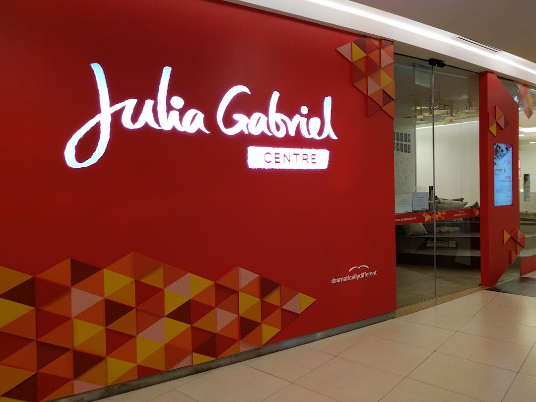 The bright red shop front of Julia Gabriel Centre with its illuminated logo and glass entrance.
