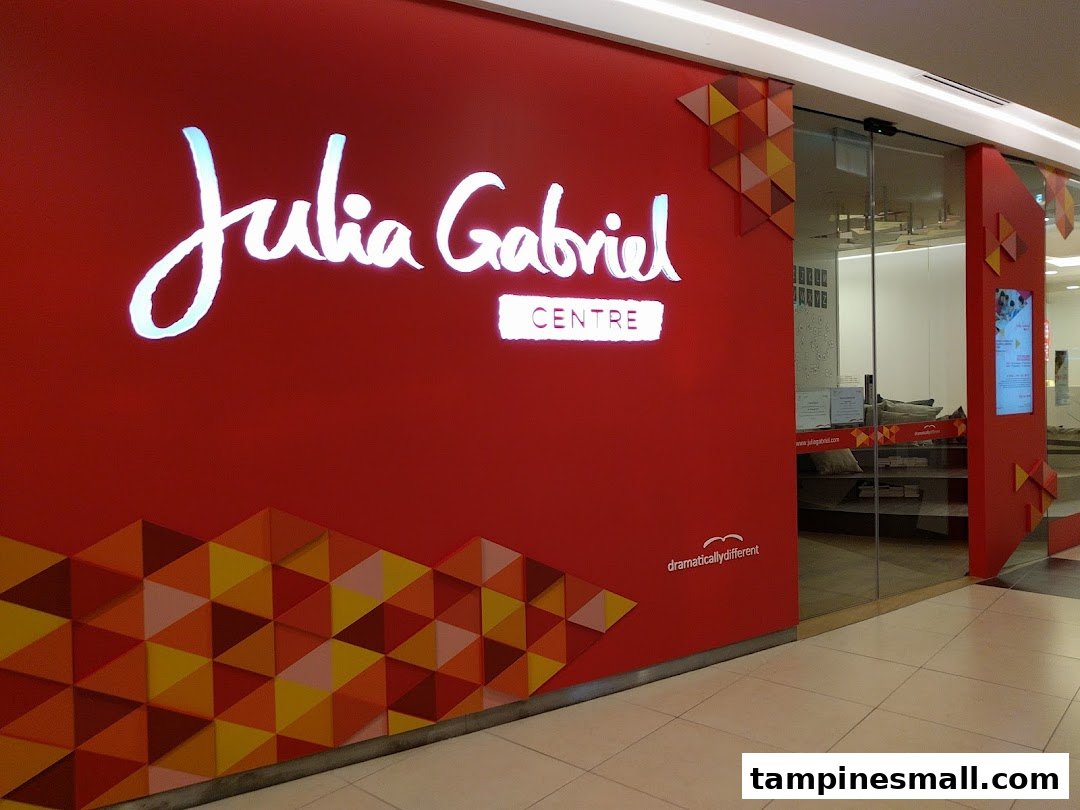 The bright red shop front of Julia Gabriel Centre with its illuminated logo and glass entrance.