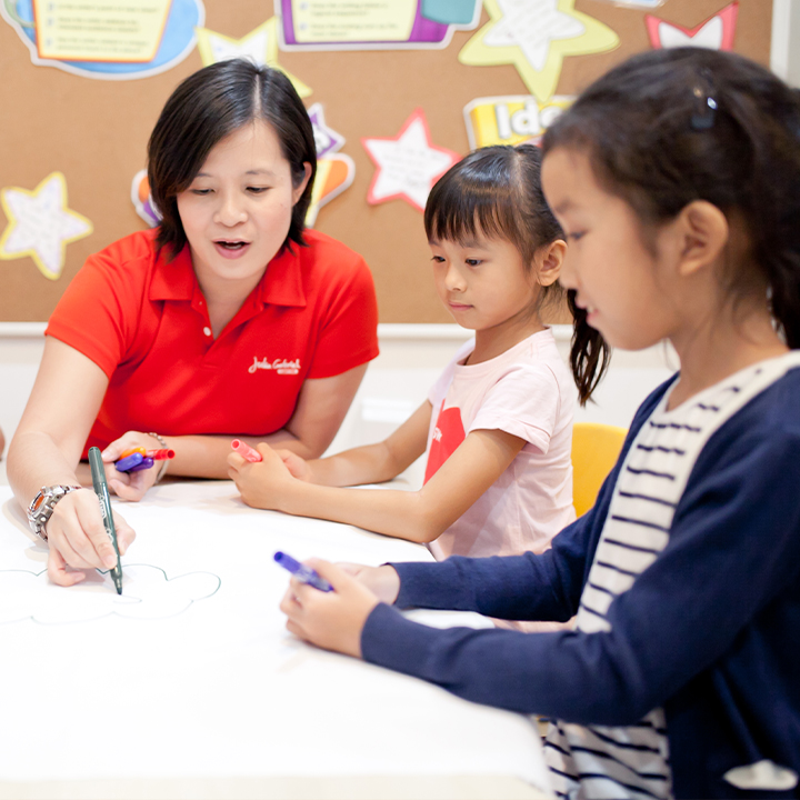 An instructor guides two children in a creative activity at Julia Gabriel Centre.