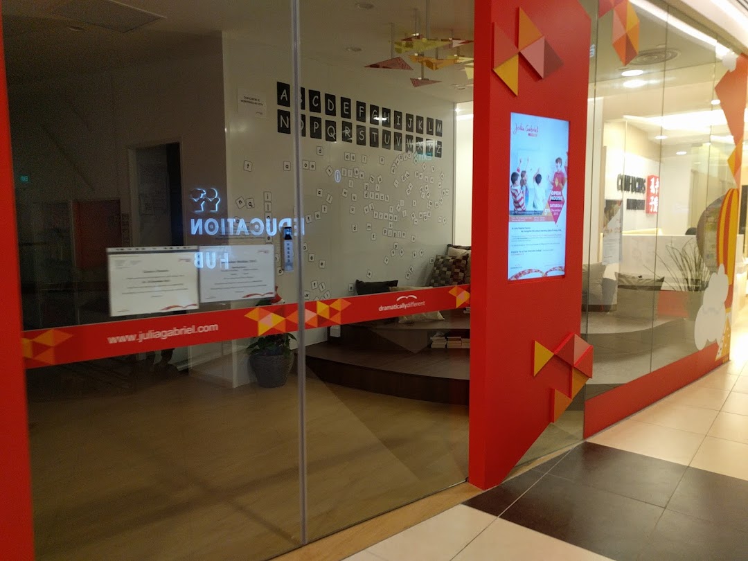 The glass entrance of Julia Gabriel Centre with red branding and a view of the interior.