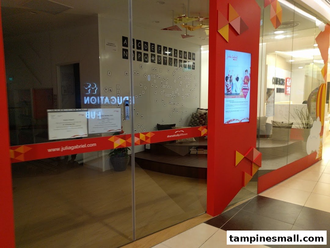 The glass entrance of Julia Gabriel Centre with red branding and a view of the interior.