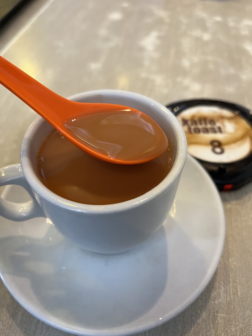A close-up of a cup of Kaffe Toast's signature beverage with an orange spoon, ready to be enjoyed.