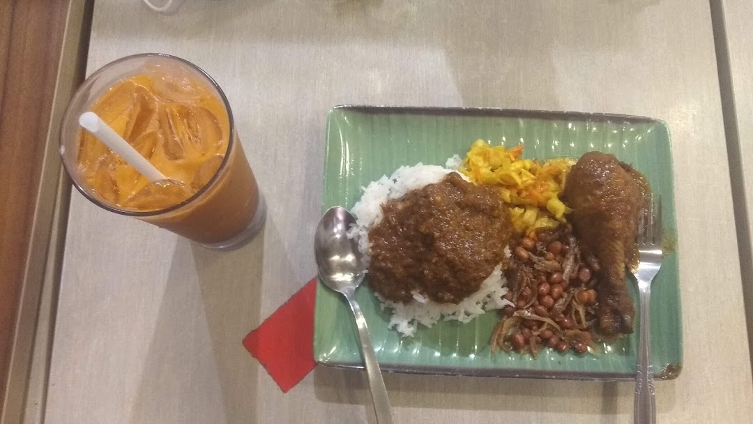 A plate of Nasi Lemak with chicken and a glass of iced milk tea.
