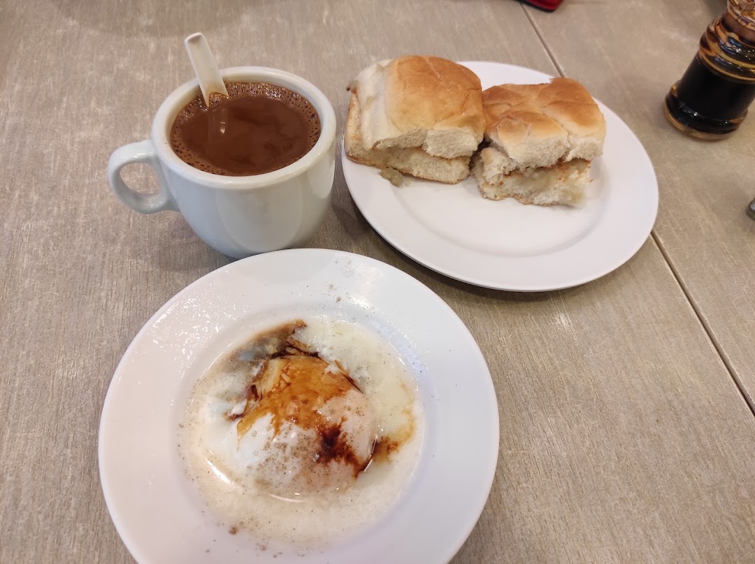A traditional Singaporean breakfast set with coffee, soft buns, and a soft-boiled egg.