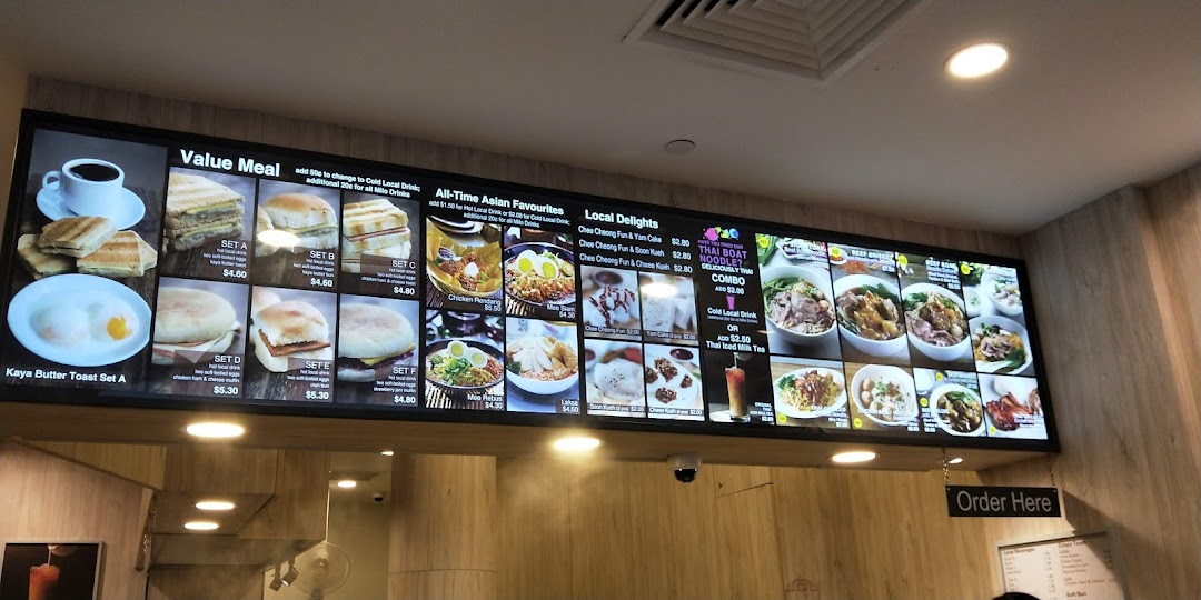 A digital menu board displaying various breakfast sets, Asian favorites, and local delights.