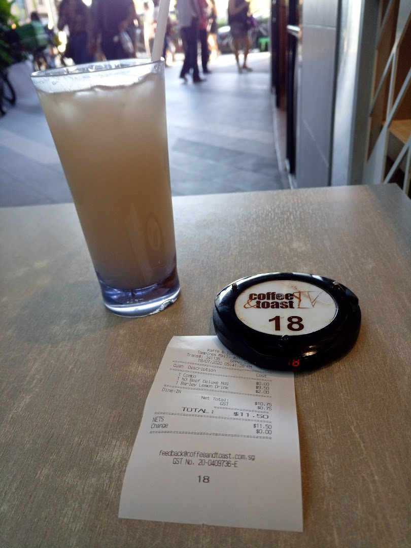 A refreshing drink, a receipt, and a pager on a table at Kaffe & Toast.