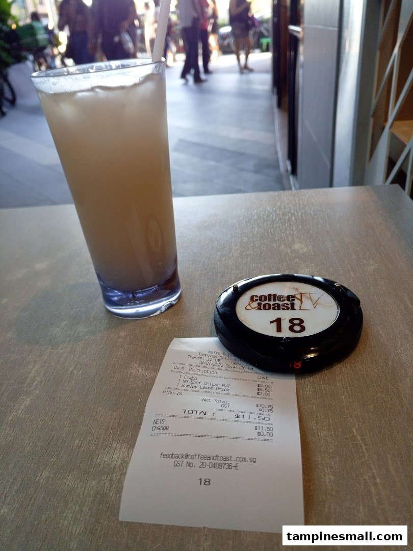 A refreshing drink, a receipt, and a pager on a table at Kaffe & Toast.