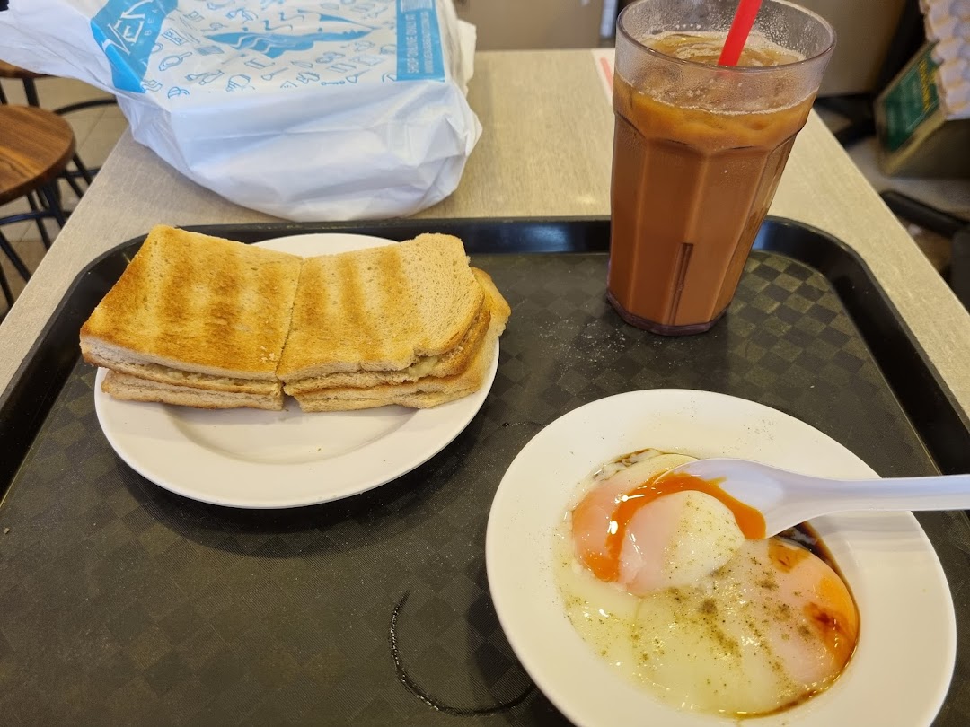 A classic Singaporean breakfast set featuring kaya toast, soft-boiled eggs, and iced coffee.