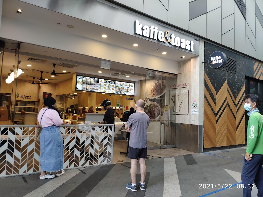 The storefront of Kaffe & Toast with its entrance, prominent signage, and customers queuing outside.