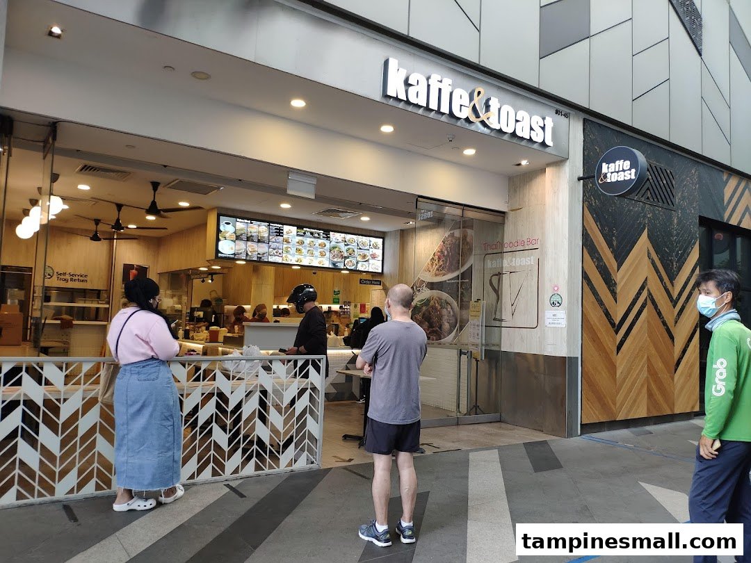 The storefront of Kaffe & Toast with its entrance, prominent signage, and customers queuing outside.