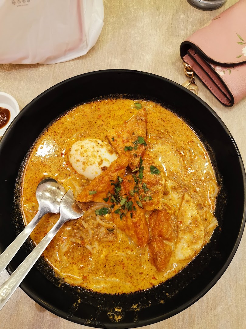 A close-up of a delicious bowl of curry noodles or laksa with egg and fried toppings.