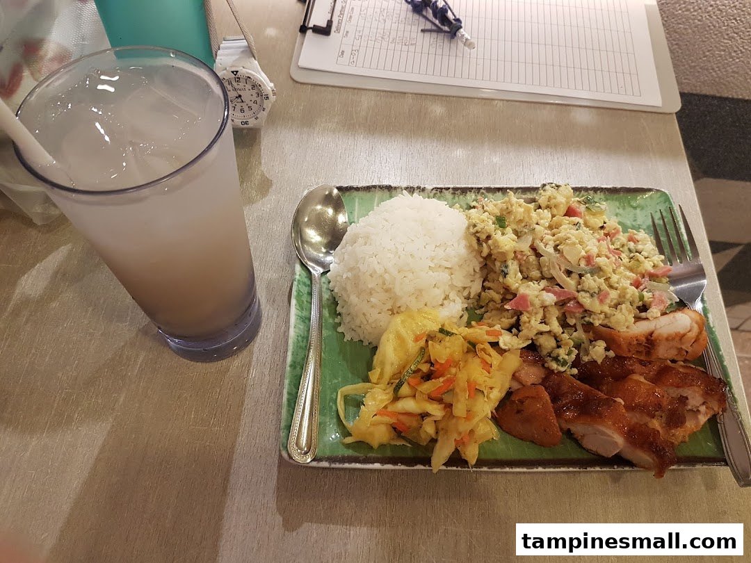 A delicious meal featuring grilled chicken, rice, scrambled eggs, and pickled vegetables, served with a refreshing drink.