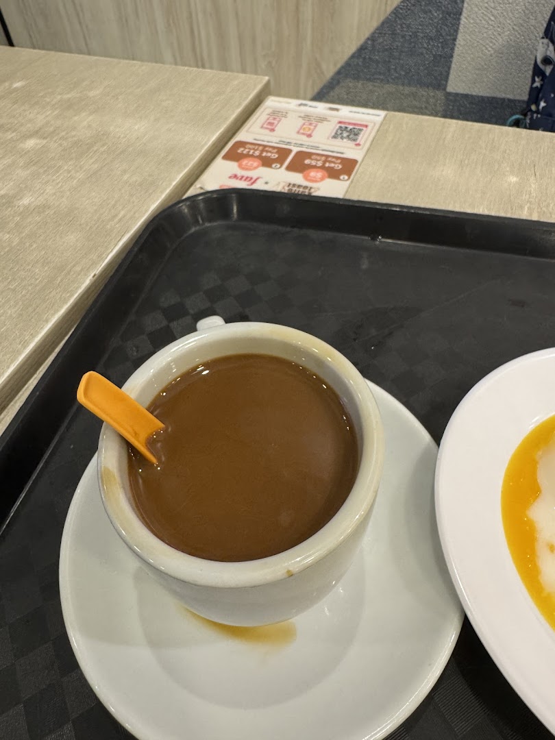 A comforting cup of coffee with an orange spoon and a plate of food on a black tray.