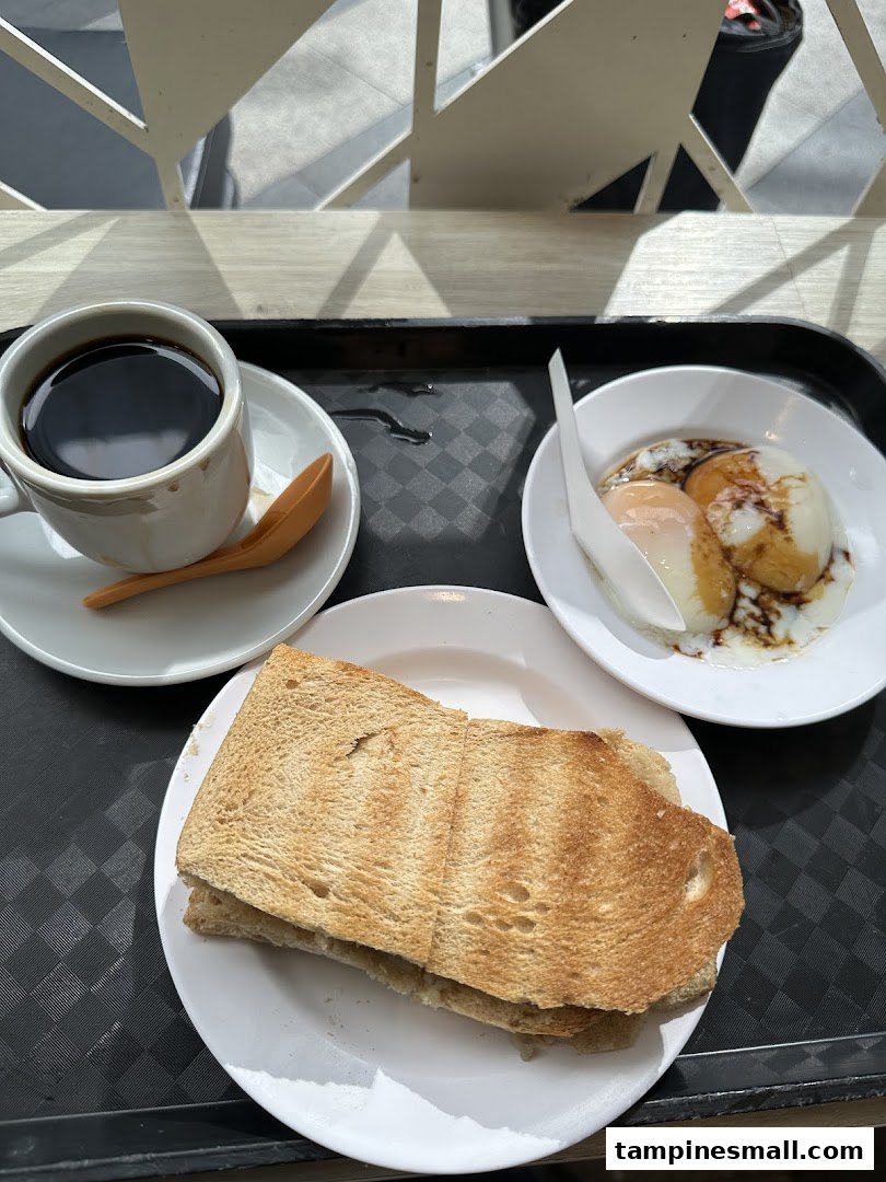 A traditional Singaporean breakfast set featuring coffee, kaya toast, and soft-boiled eggs.
