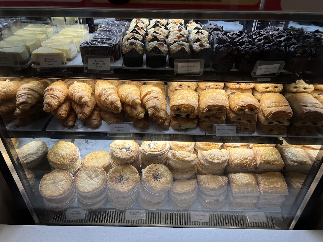 A vibrant display case showcasing a variety of freshly baked pastries, cakes, and savory pies.