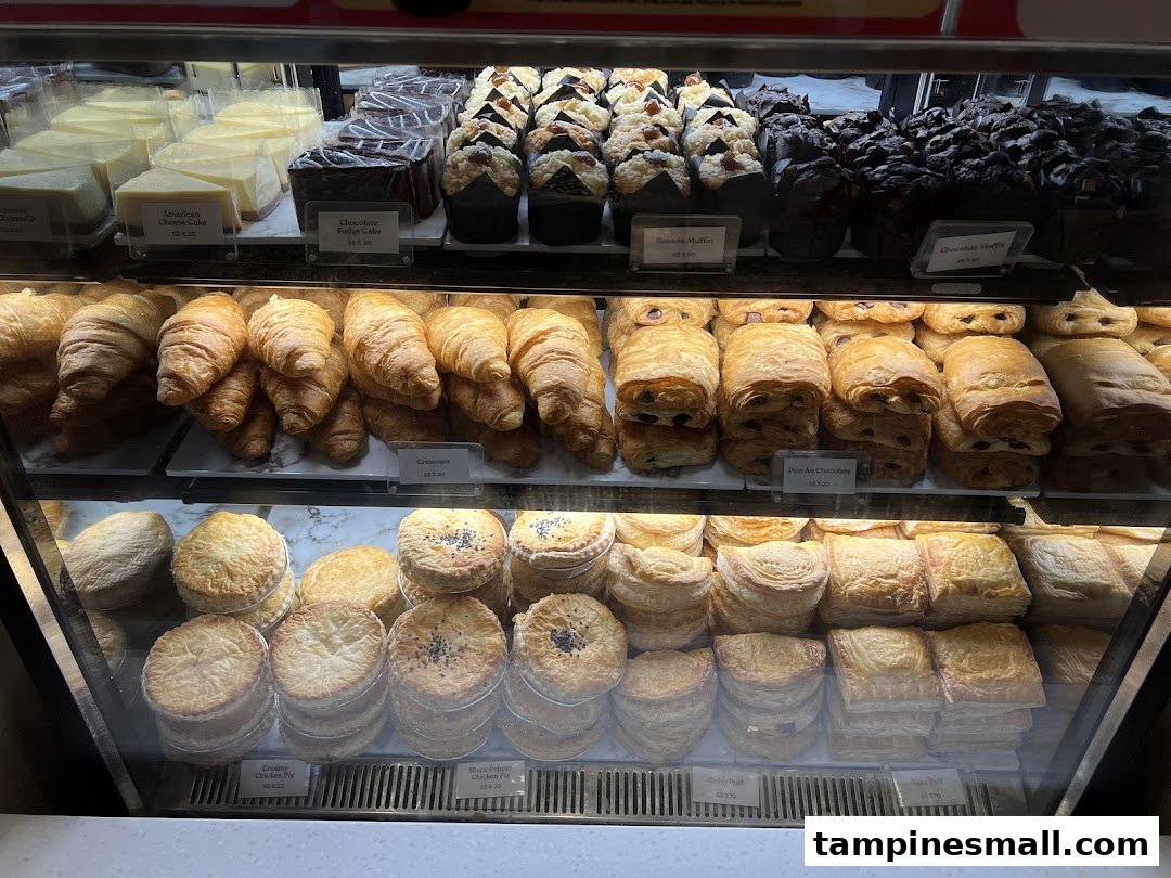 A vibrant display case showcasing a variety of freshly baked pastries, cakes, and savory pies.