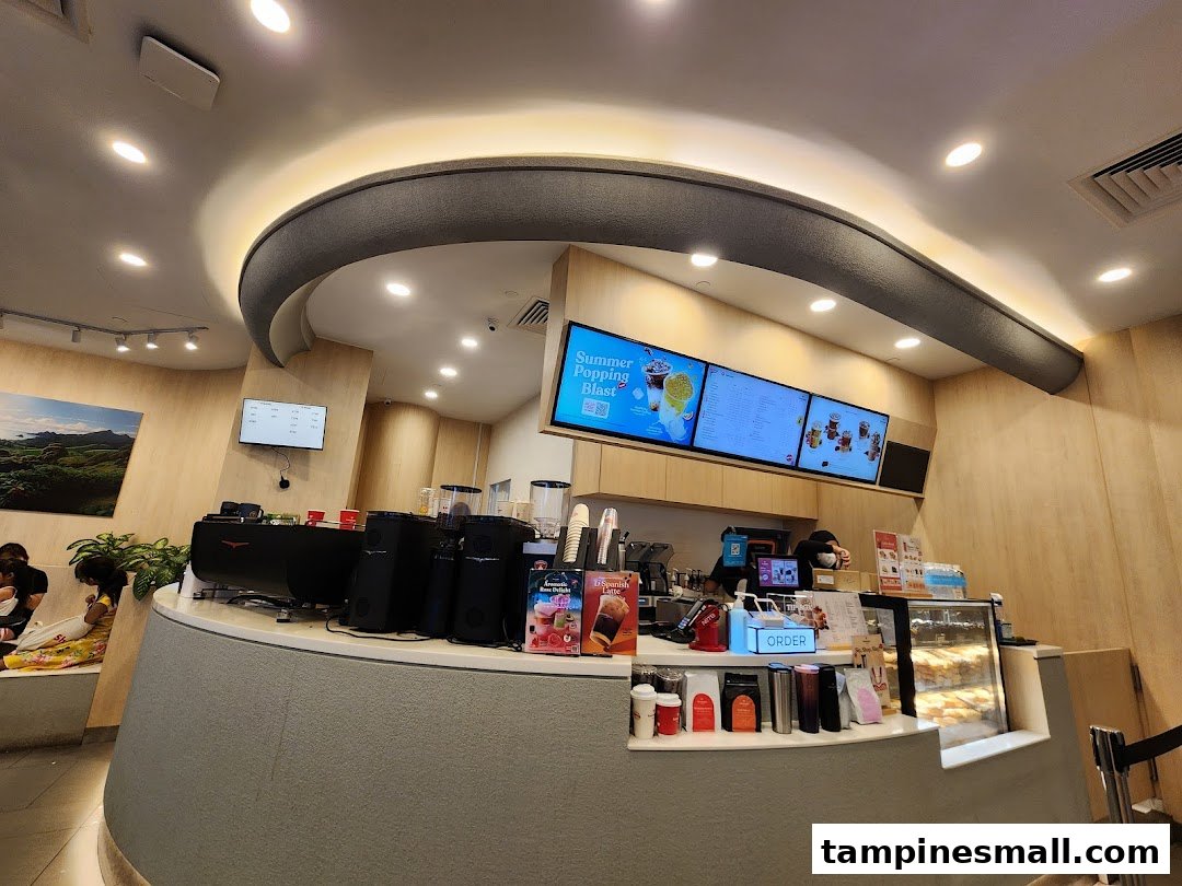 Interior view of Kenangan Coffee, featuring the service counter, digital menu boards, and a cozy seating area.