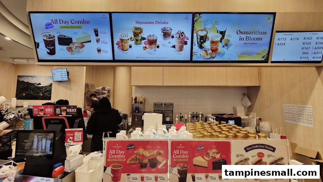 Interior view of Kenangan Coffee's counter, featuring digital menu boards, physical displays, and staff.
