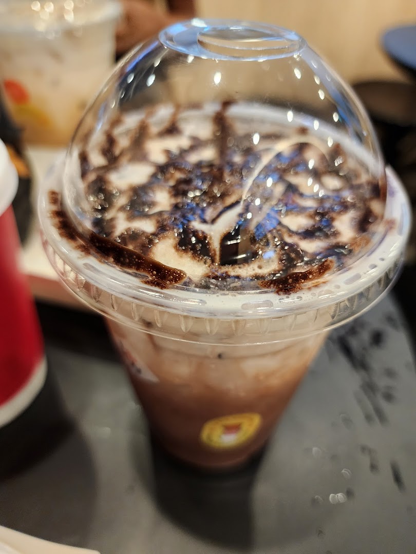 A close-up of a chocolate-drizzled iced coffee drink with a clear dome lid from Kenangan Coffee.