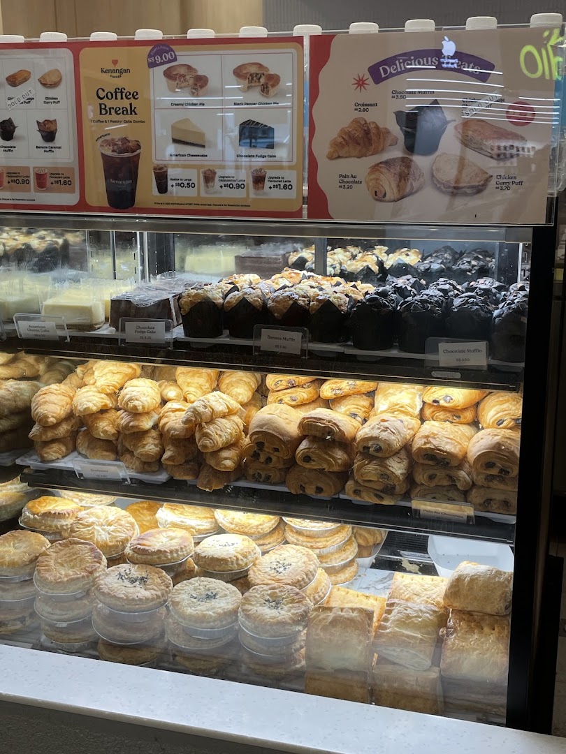 A display case filled with various pastries and cakes, topped with menu boards detailing coffee and treat options.