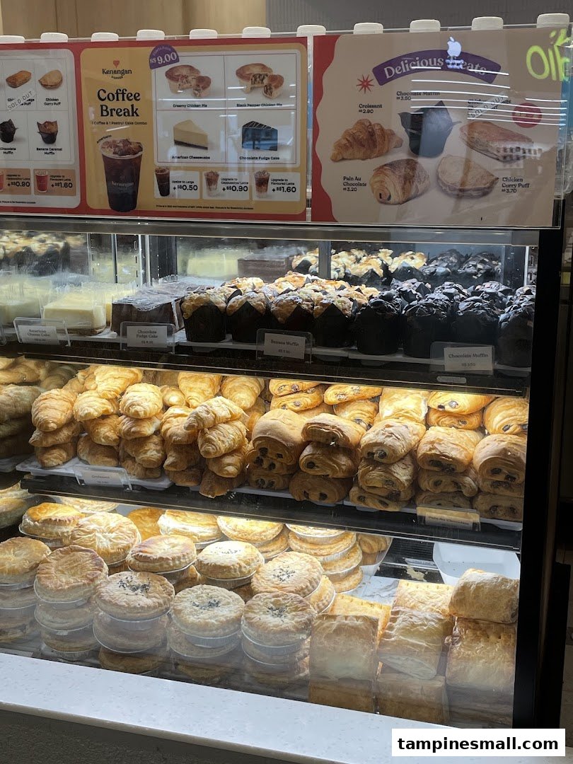 A display case filled with various pastries and cakes, topped with menu boards detailing coffee and treat options.