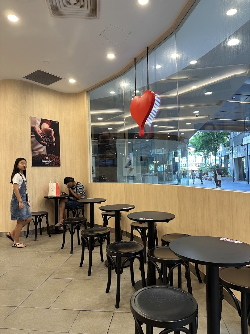 Interior view of Kenangan Coffee showing the seating area and large window.