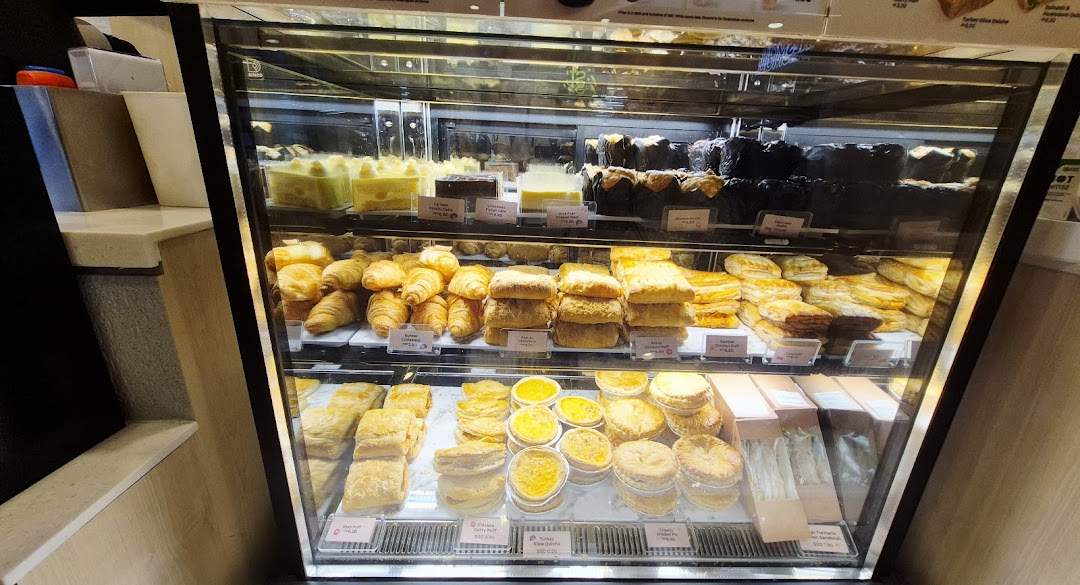 A glass display case showcasing a wide assortment of freshly baked pastries, cakes, and savory items.