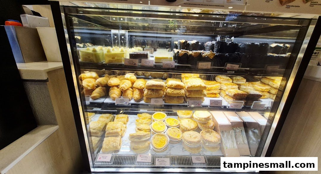 A glass display case showcasing a wide assortment of freshly baked pastries, cakes, and savory items.