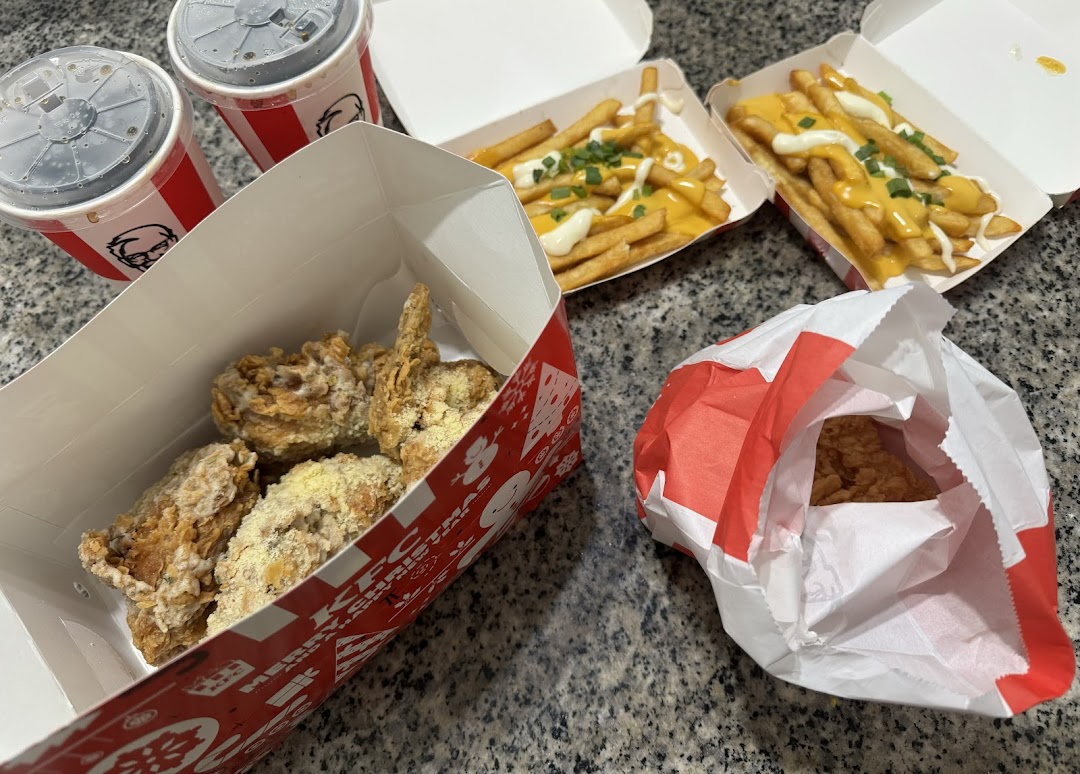 A delicious KFC meal featuring fried chicken, cheesy fries, and refreshing drinks.