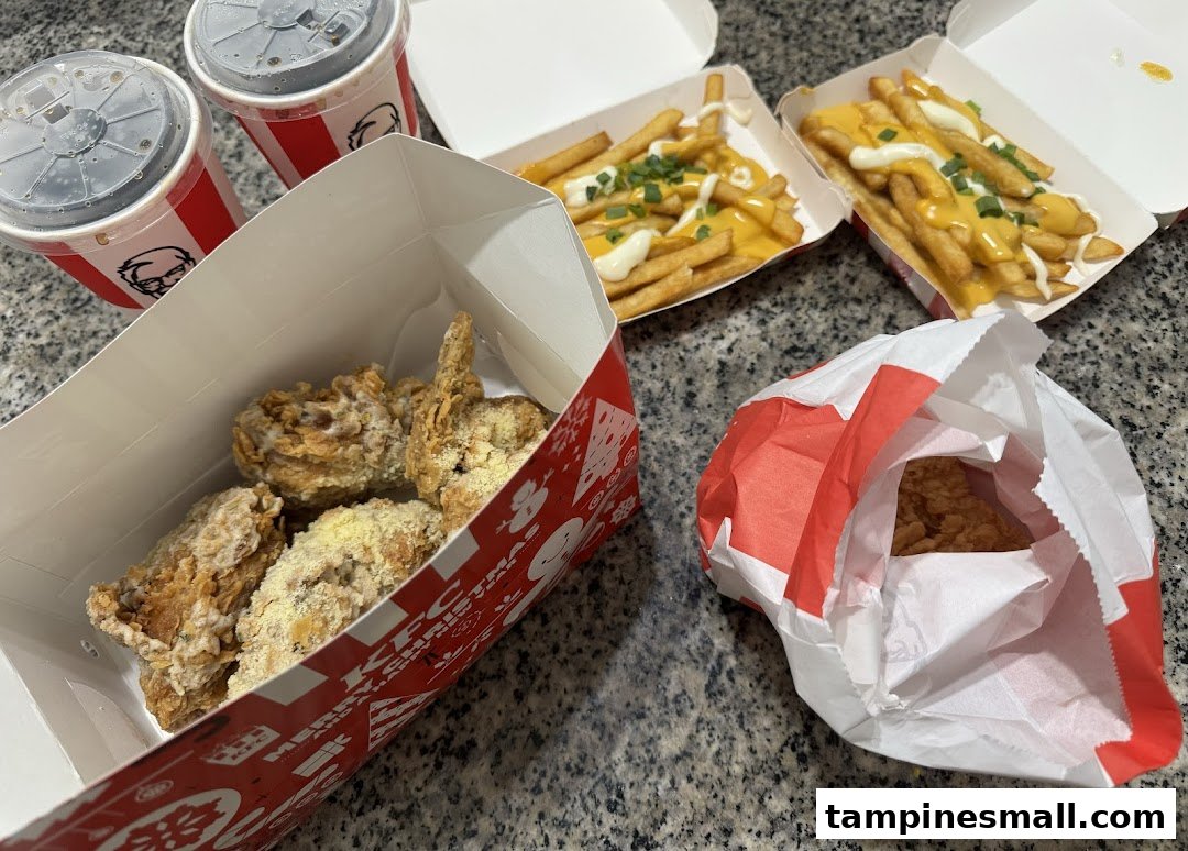 A delicious KFC meal featuring fried chicken, cheesy fries, and refreshing drinks.