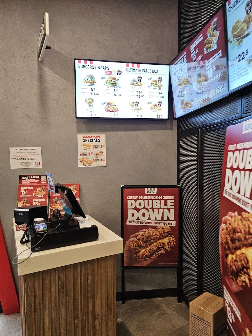 Interior view of KFC featuring digital menu boards, a service counter, and promotional signage.