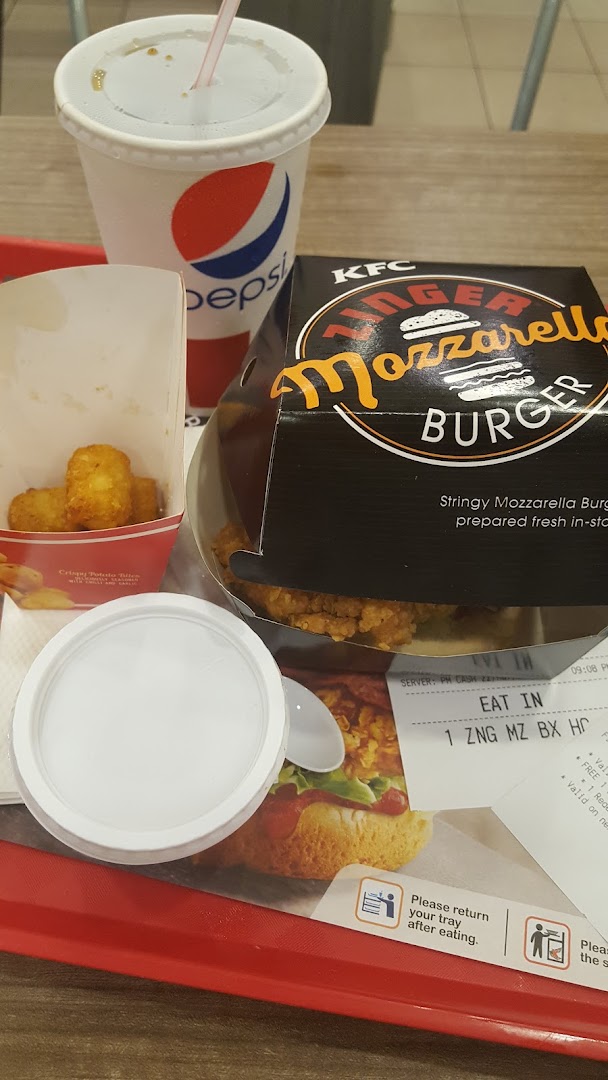 A KFC meal featuring a Zinger Mozzarella Burger, potato tots, and a Pepsi drink on a red tray.