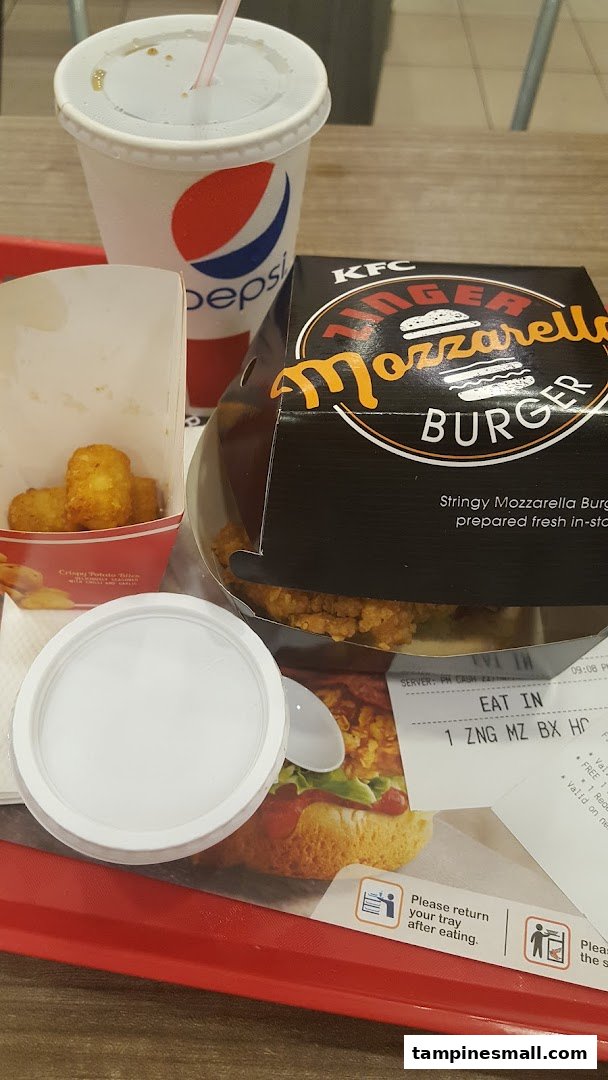 A KFC meal featuring a Zinger Mozzarella Burger, potato tots, and a Pepsi drink on a red tray.
