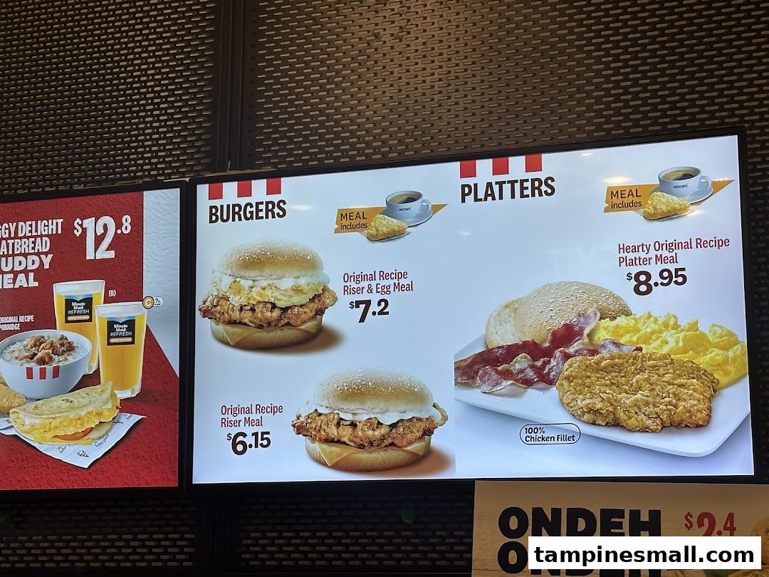 A digital menu board at KFC displaying various meal options, including burgers, platters, and breakfast items.