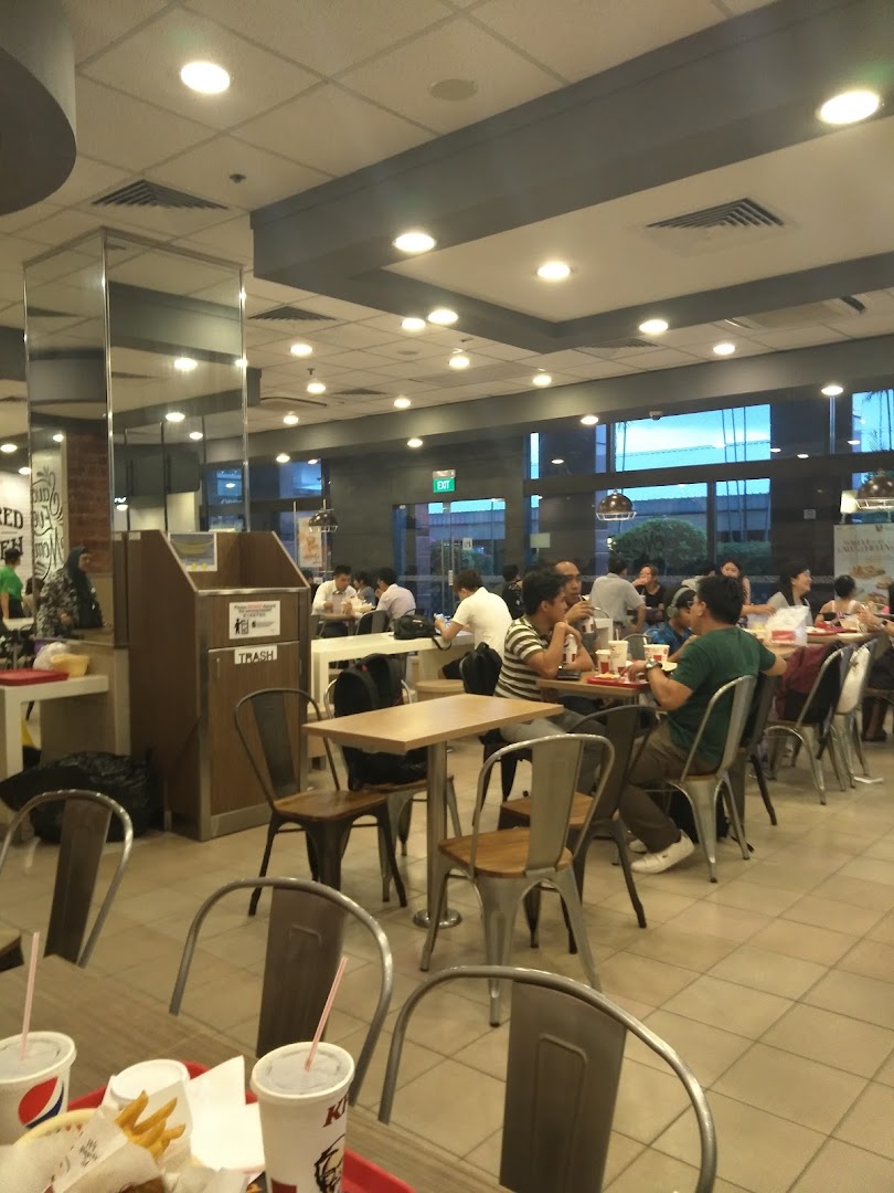 Customers enjoy meals inside a bustling KFC restaurant with modern interior design.