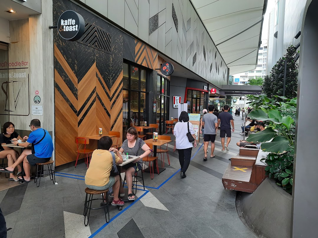 Exterior view of a bustling mall walkway featuring KFC and Kaffe & Toast with outdoor seating.