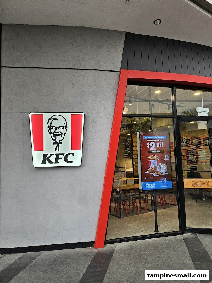 The exterior of a KFC restaurant featuring its iconic logo and a glimpse into the dining area.