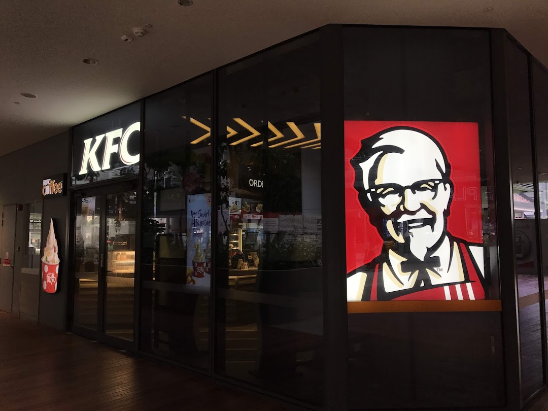 The illuminated KFC storefront features its iconic logo and a large Colonel Sanders graphic.