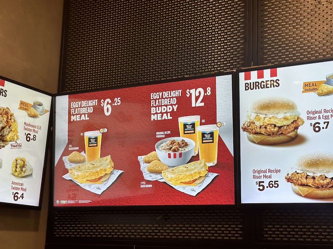 A brightly lit KFC menu board displaying breakfast and burger options with prices.